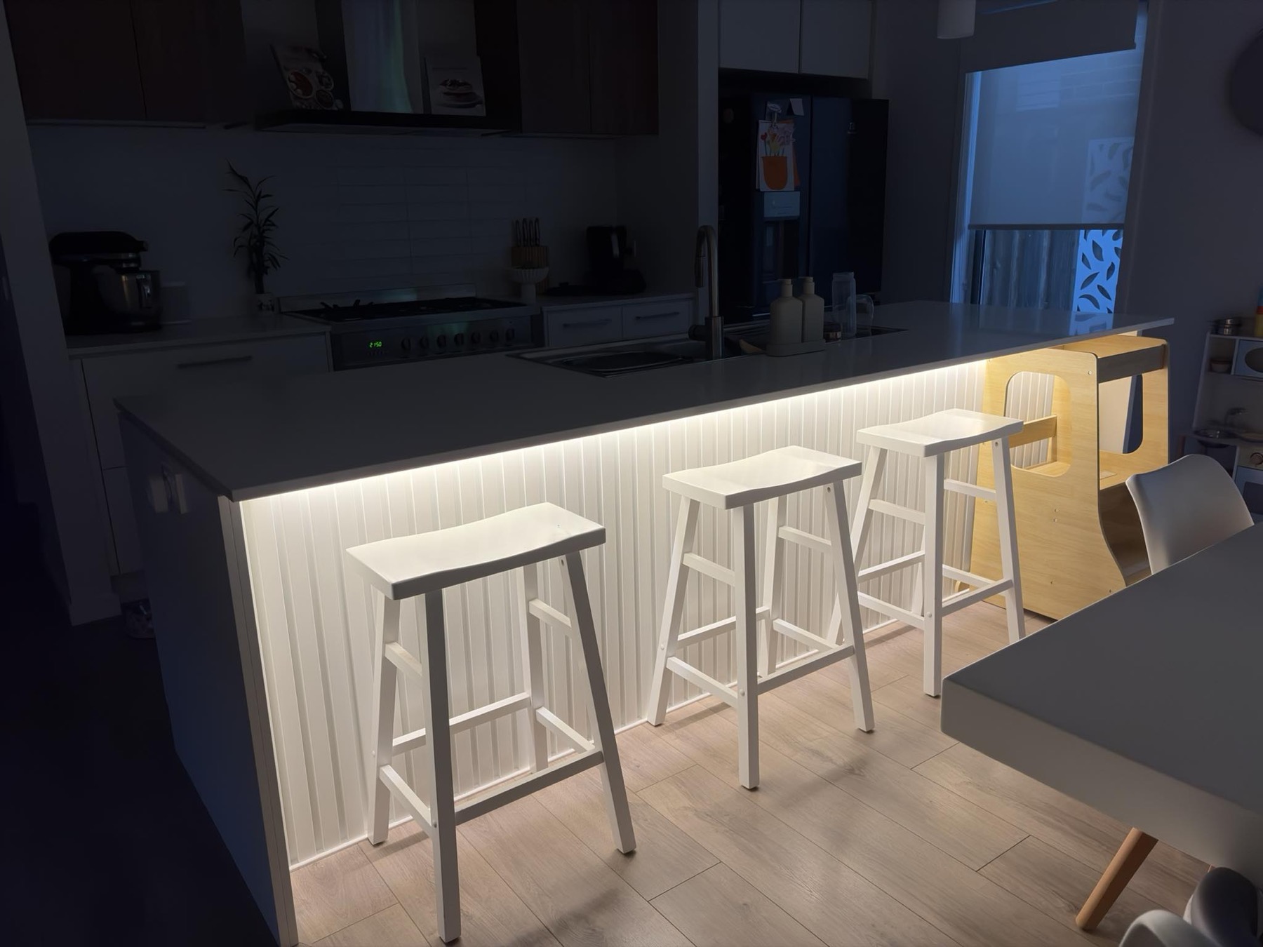 Kitchen island with lit panel detail and bar stools
