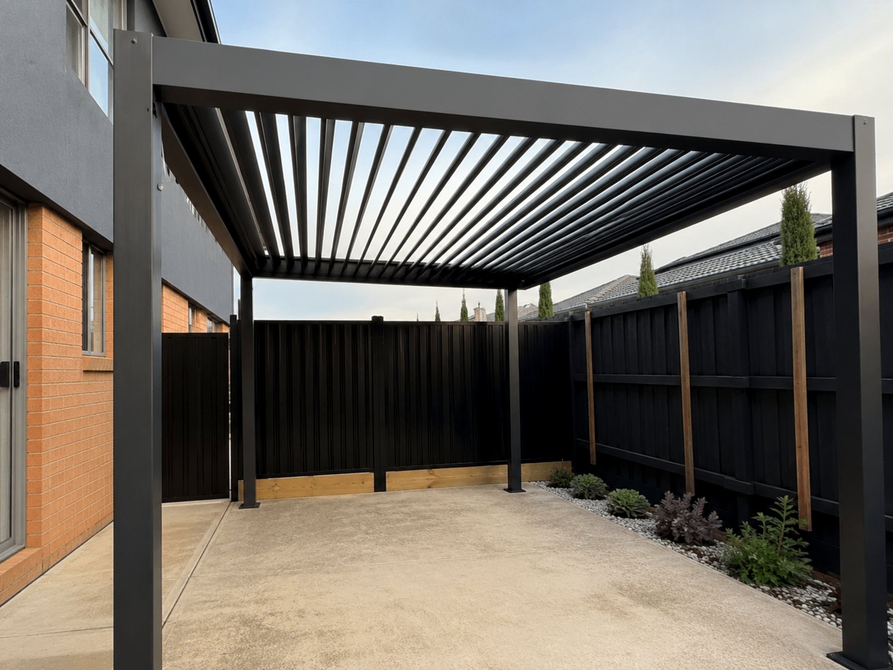 Finished black pergola and outdoor cover work over a backyard patio area