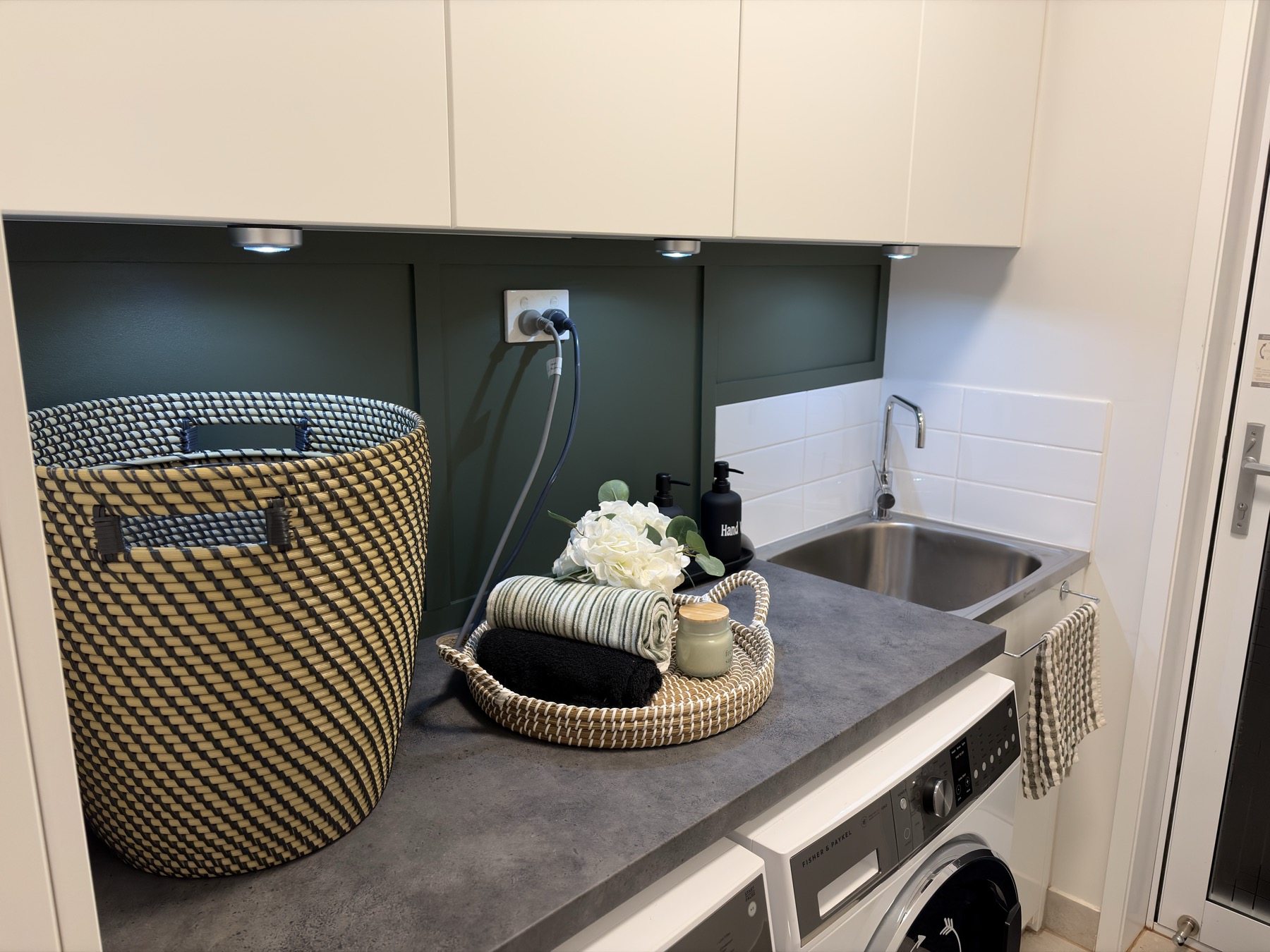 Finished laundry wall treatment with green panel detail, bench, sink and cupboards
