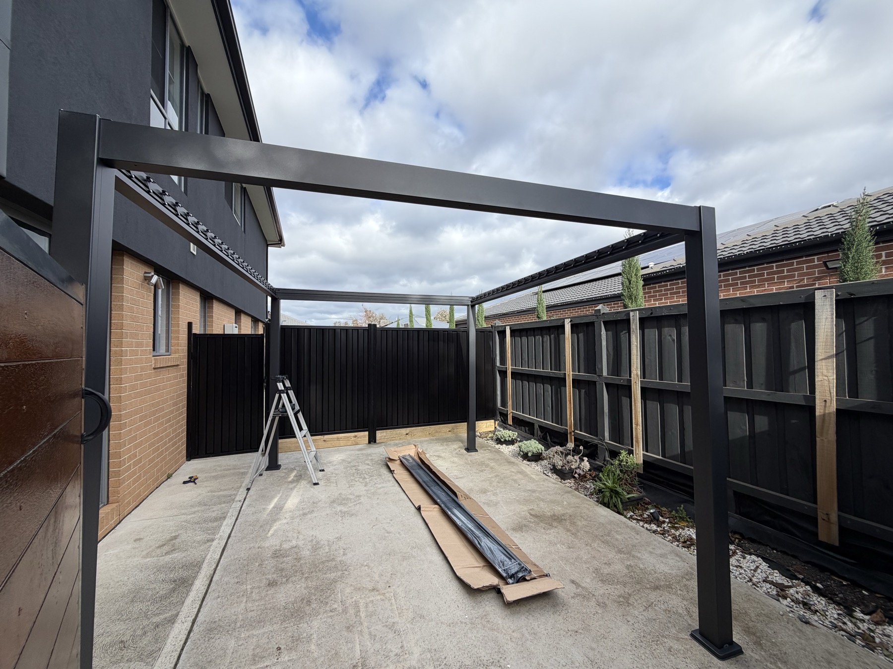 Pergola frame under construction in a backyard patio area